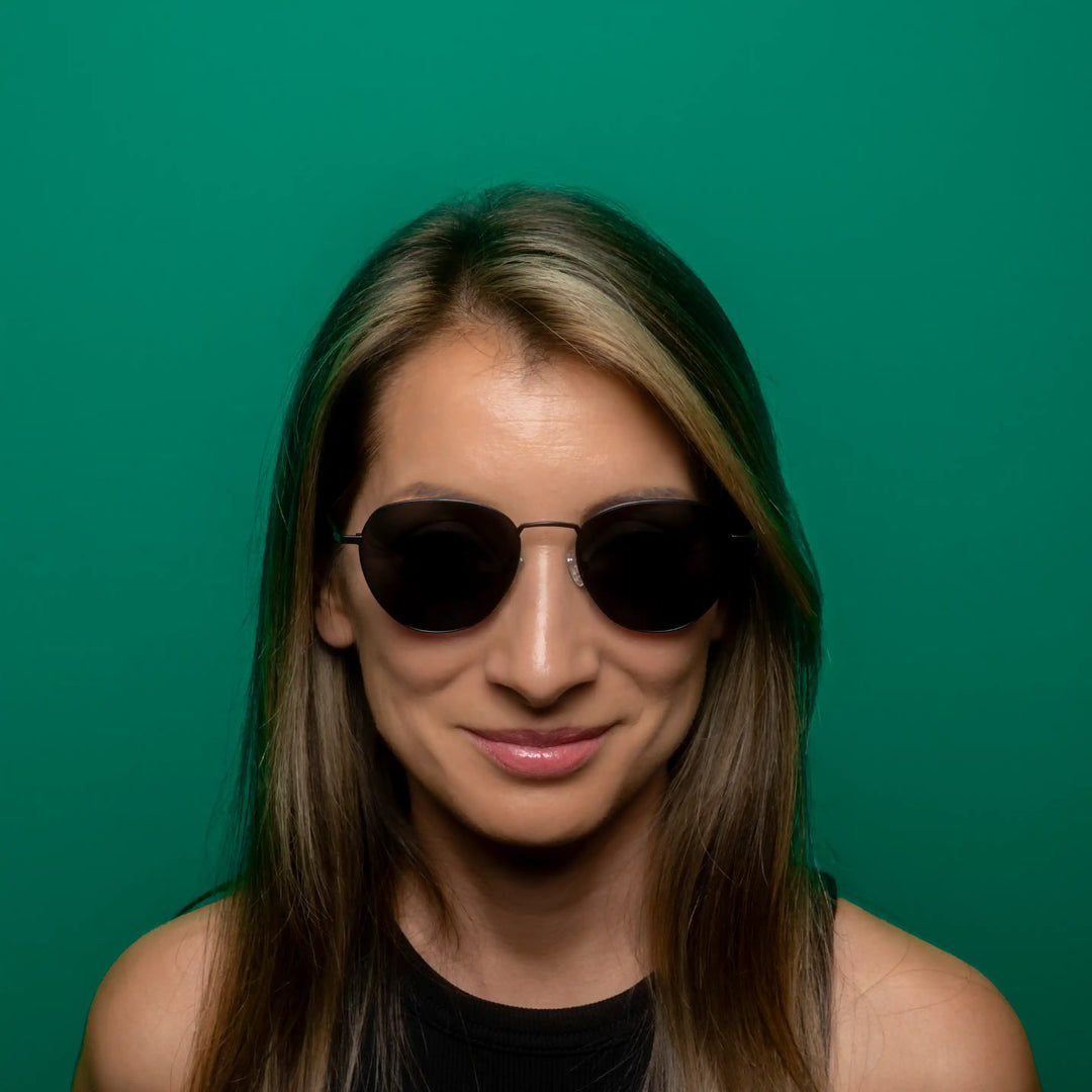 Woman wearing sunglasses against a green background