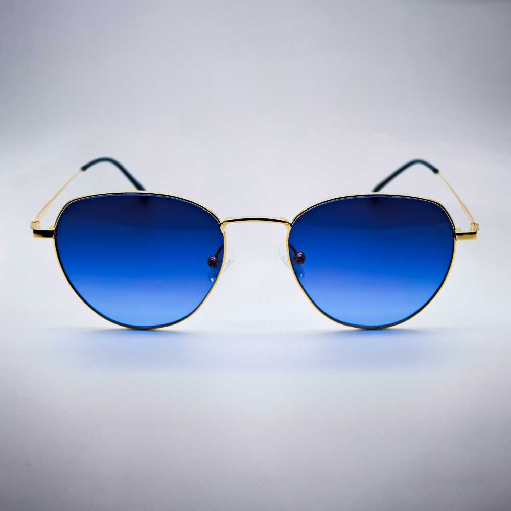 Sunglasses with blue lenses and gold frames on a light gray background #desktop-half for half-width