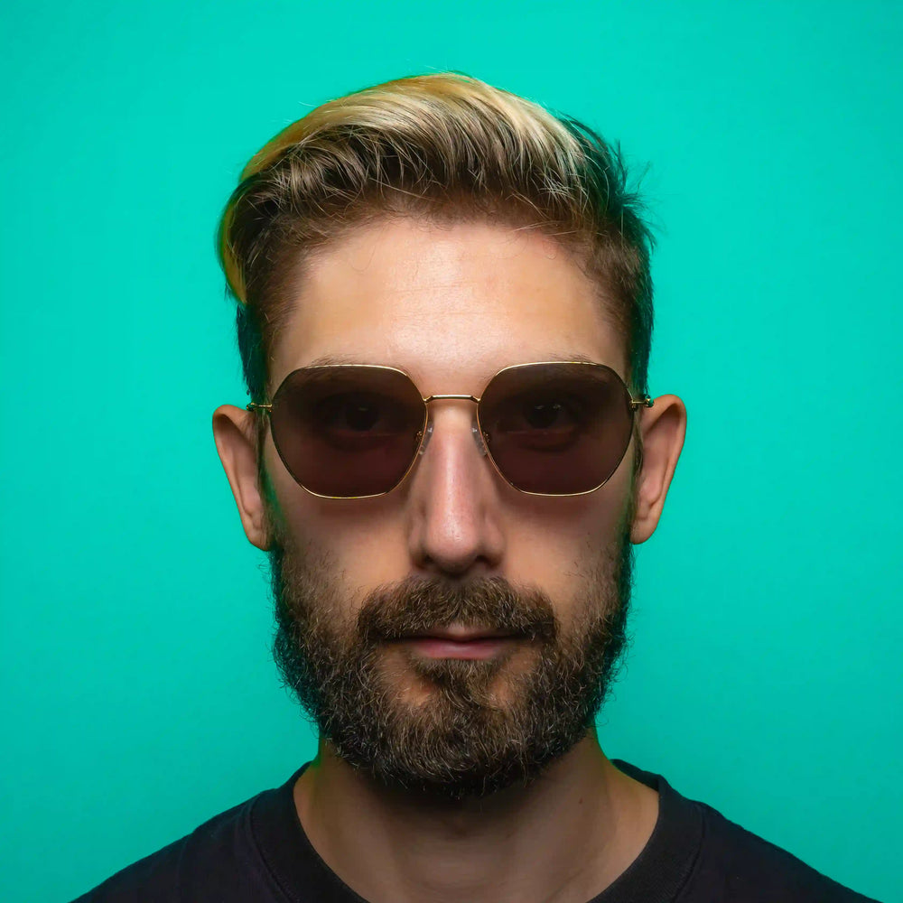 Man wearing geometric sunglasses against a teal background