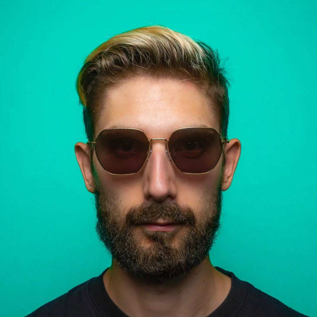 Man wearing geometric sunglasses against a teal background