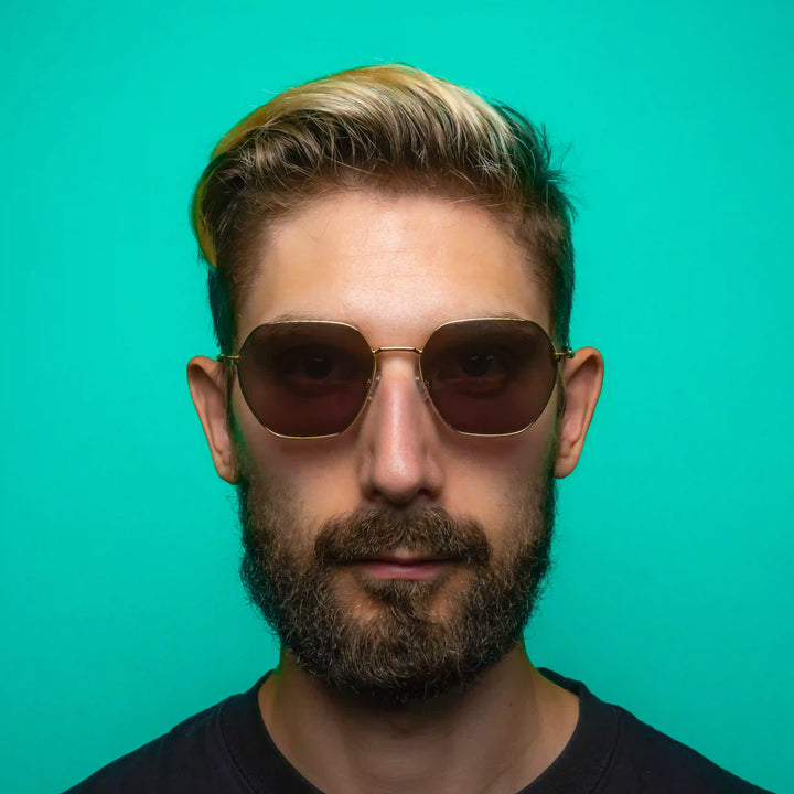 Man wearing geometric sunglasses against a teal background