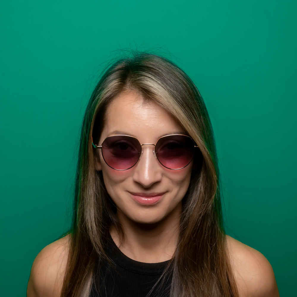 Woman wearing pink sunglasses against a green background