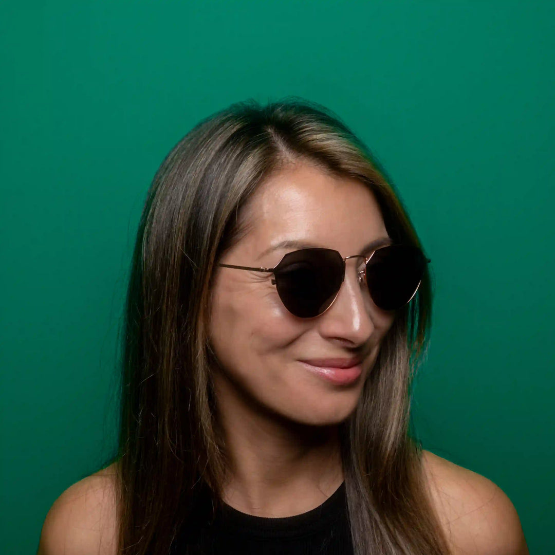 Woman wearing sunglasses against a green background